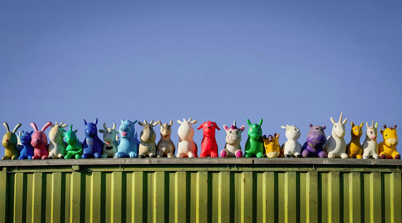 Plastic animal figurines of all colours and shapes are aligned on the edge of a container